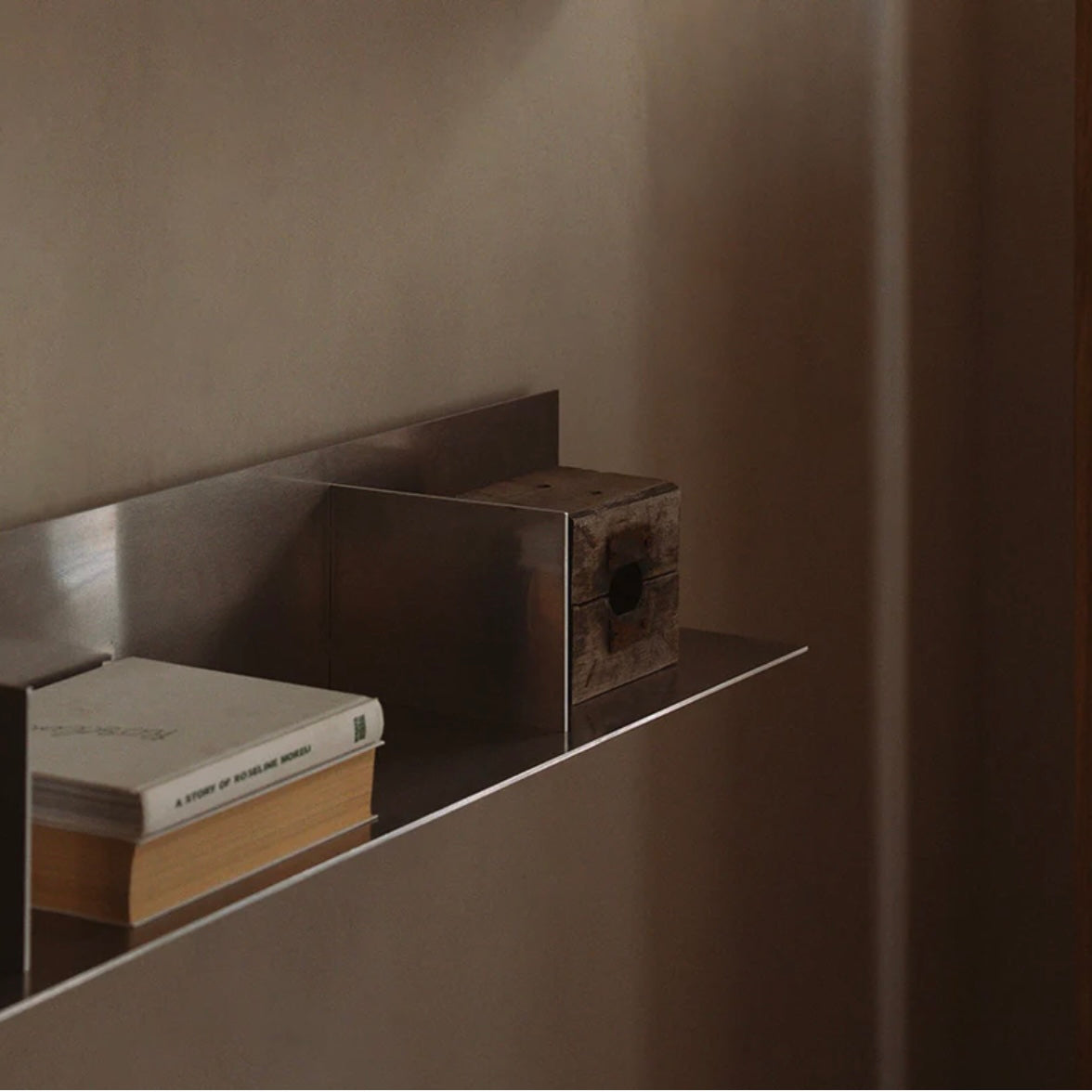 Modern metal shelf with books against a neutral wall