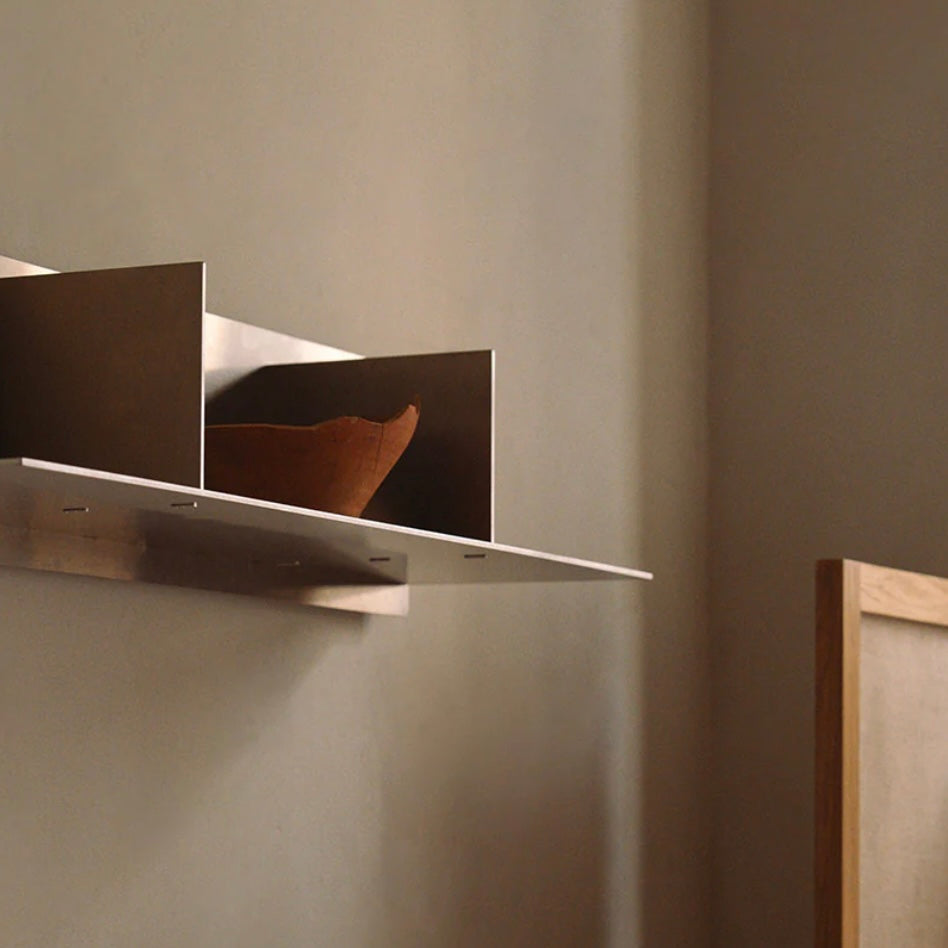 Metallic wall shelf against a plain wall