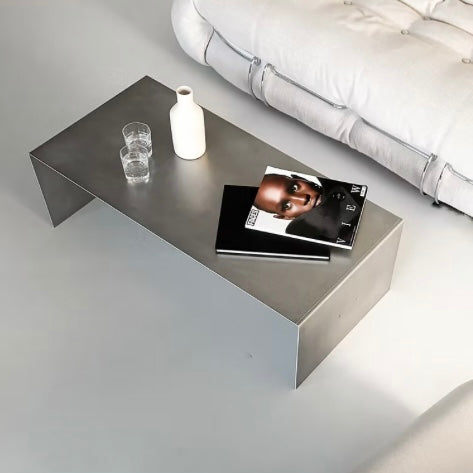 Modern coffee table with a vase, glasses, and book in a minimalistic living room.