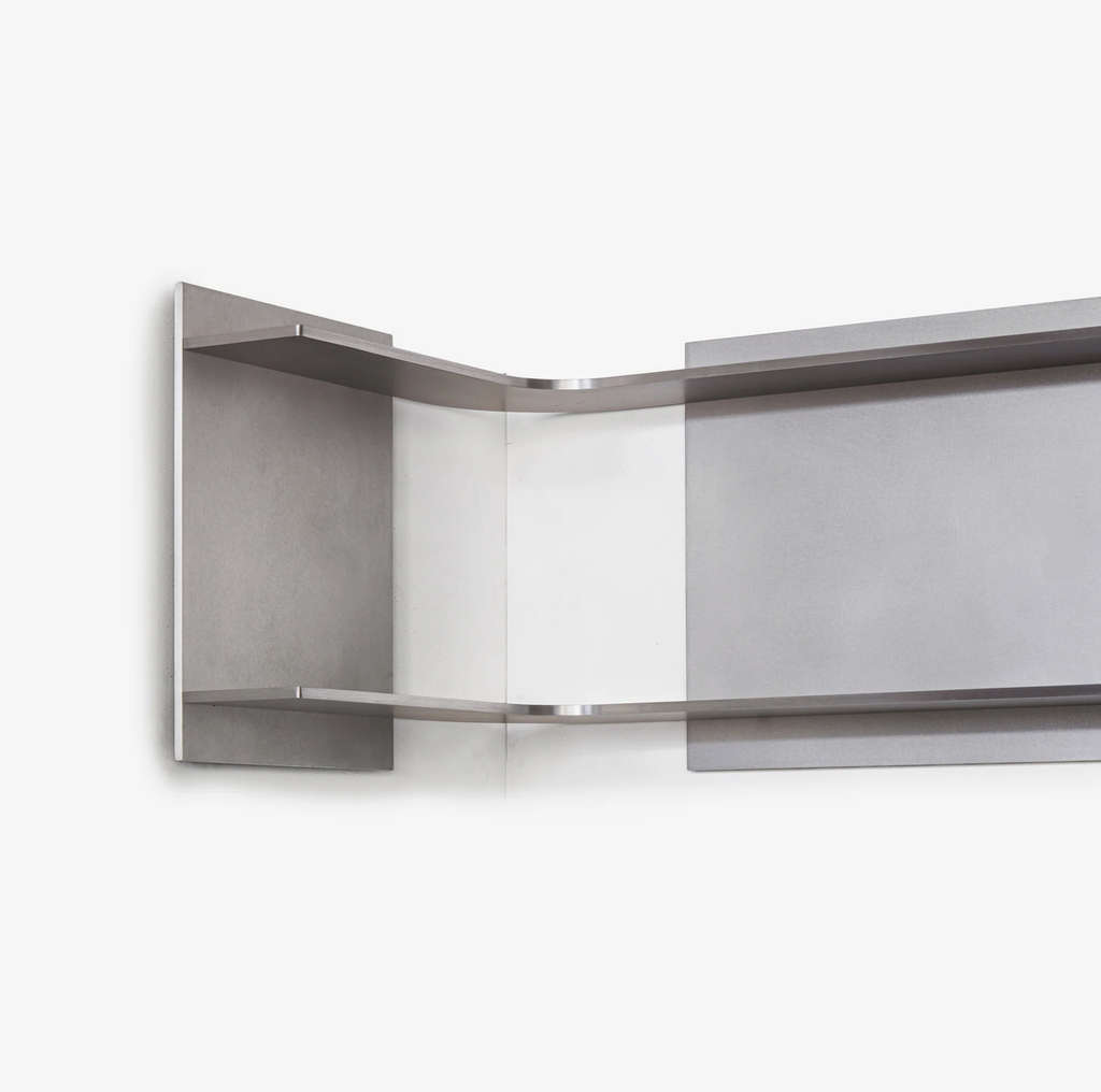 Modern wall-mounted metal shelf with a reflective surface on a white background